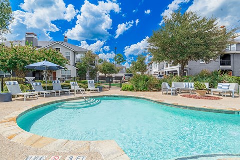 A swimming pool surrounded by lounge chairs and umbrellas.