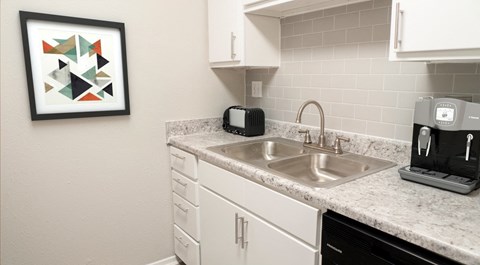 A modern kitchen with a white dishwasher and a silver sink.