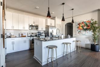 a kitchen with white cabinets and a large island with three stools