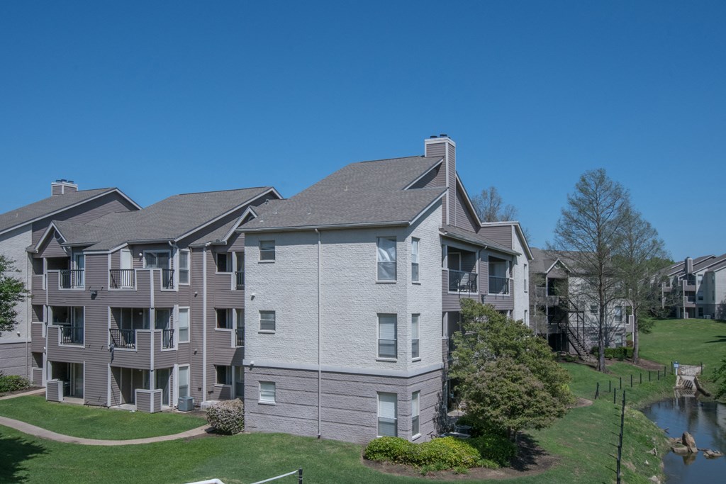 a view of an apartment complex with a pond in the foreground