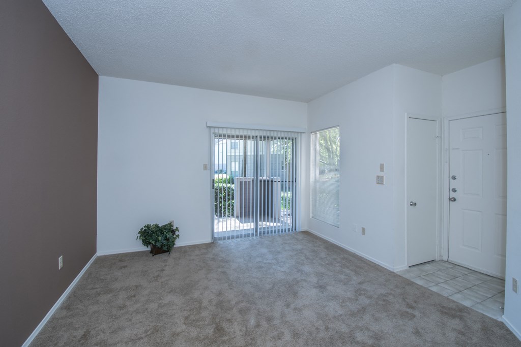 an empty living room with a door leading to a balcony