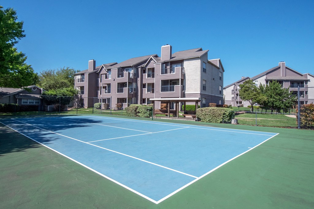 a tennis court at the whispering winds apartments in pearland, tx