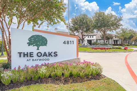 A sign for "The Oaks at Baywood" is displayed in front of a building.