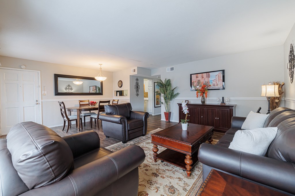 a living room with leather furniture and a dining room with a table and chairs