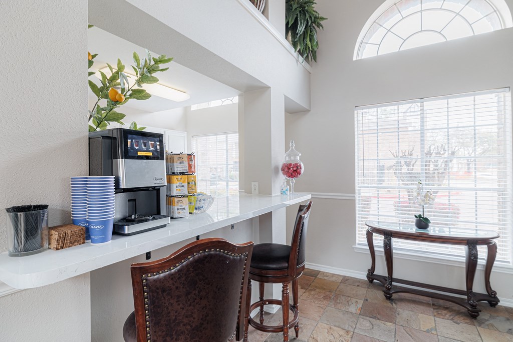 a kitchen with a coffee machine and a counter with chairs