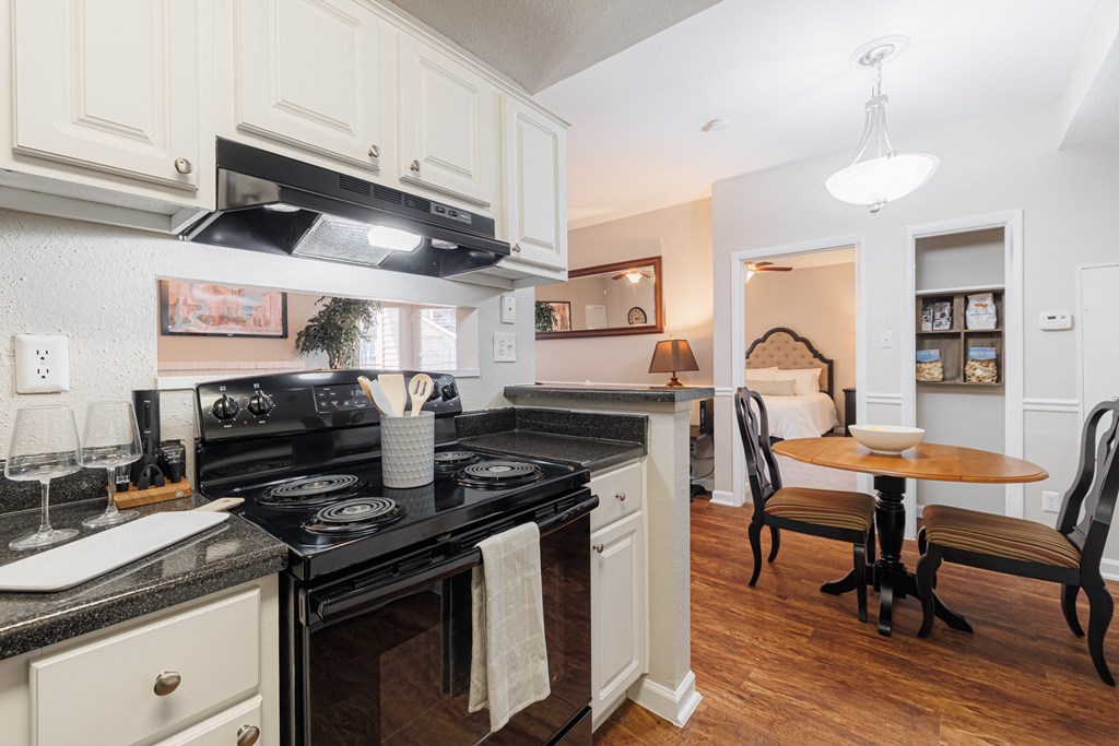 a kitchen with a stove and a dining room with a table