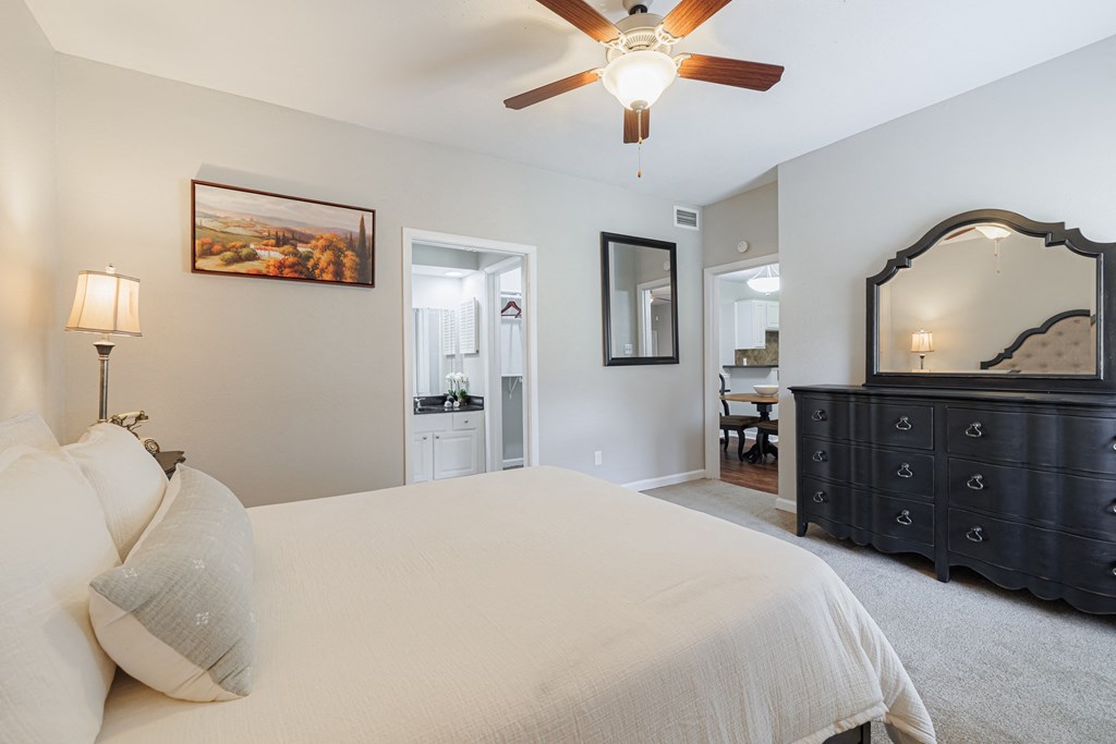 a bedroom with a bed and a dresser and a ceiling fan
