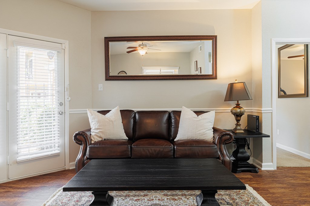 a living room with a leather couch and a mirror