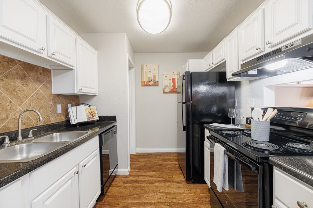 a kitchen with white cabinets and black counter tops