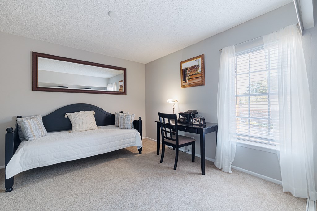 A bedroom with a bed, desk, and chair.