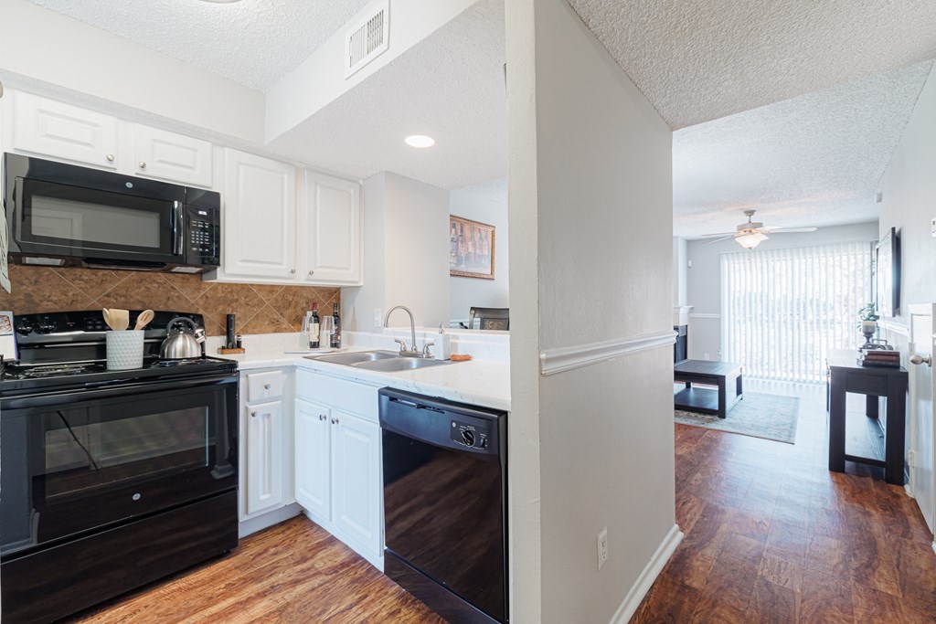 A kitchen with black appliances and white cabinets.
