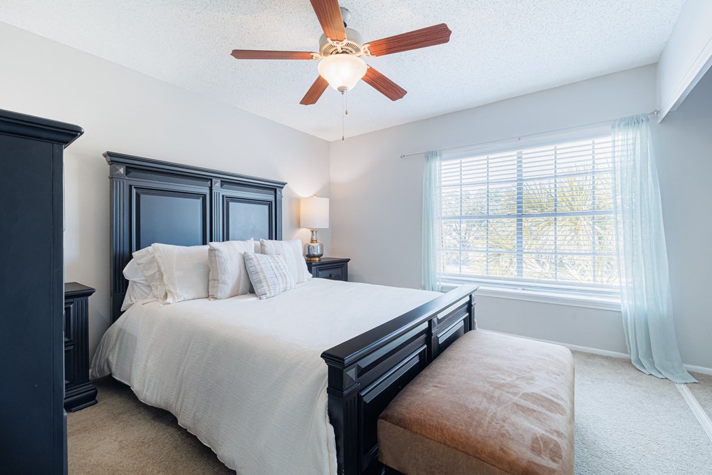 A bedroom with a bed, nightstand, and window.