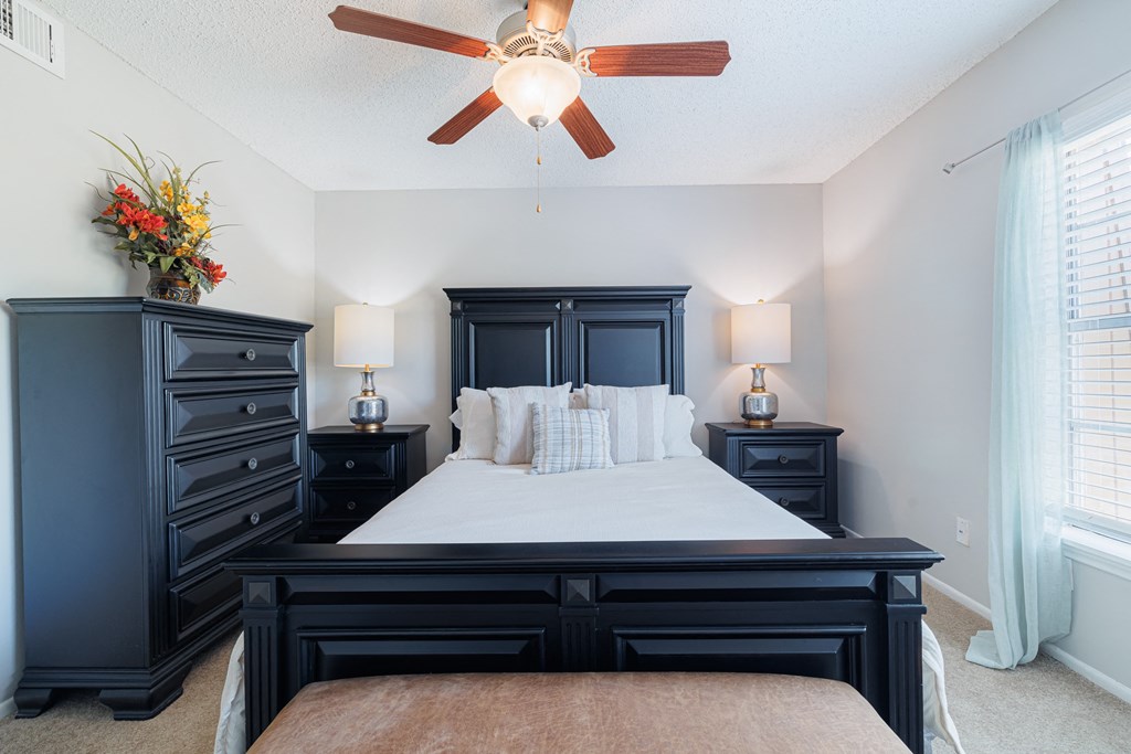 A bedroom with a large bed and a ceiling fan.