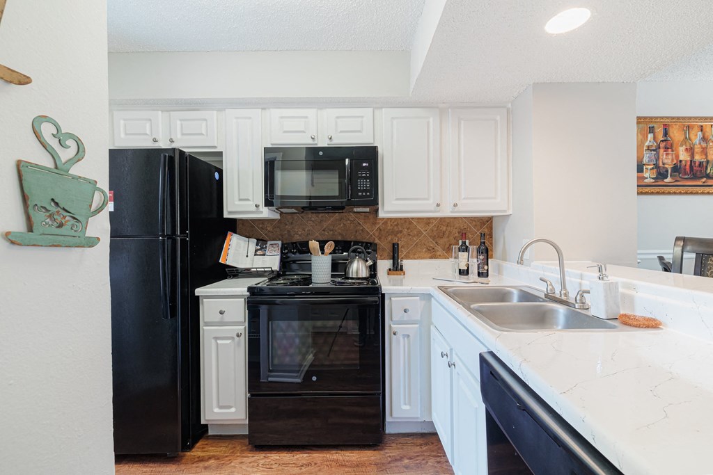 A kitchen with black appliances and white cabinets.