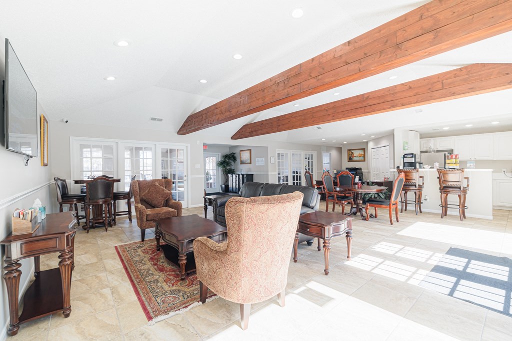 A living room with a wooden ceiling beam and a rug on the floor.