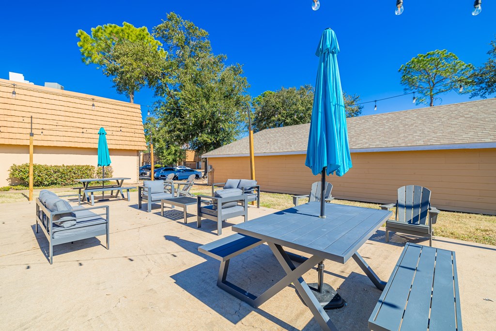 A blue umbrella is on a table in a sandy area.