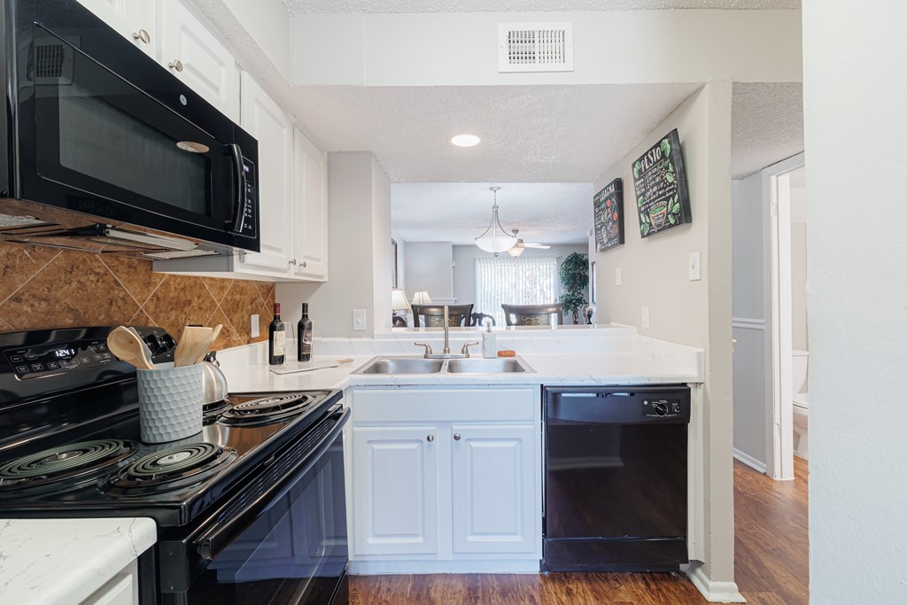 A kitchen with black appliances and white cabinets.
