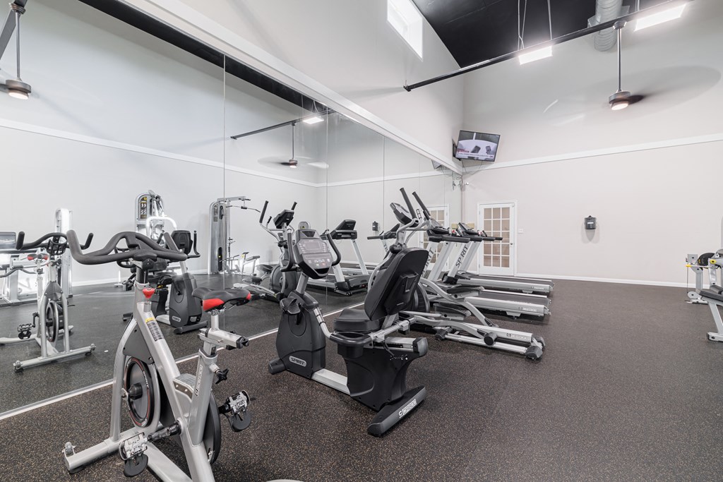 A gym with a variety of exercise equipment including treadmills, stationary bikes, and weight machines.