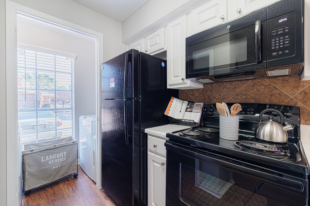 A black refrigerator sits next to a white oven in a kitchen.