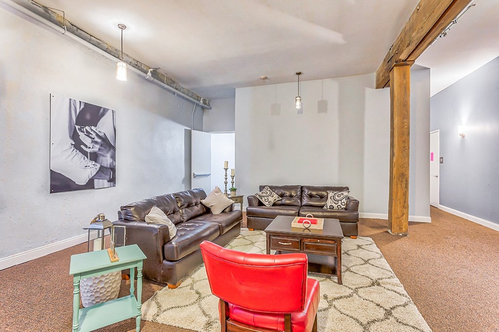 a living room with two leather couches and a red chair