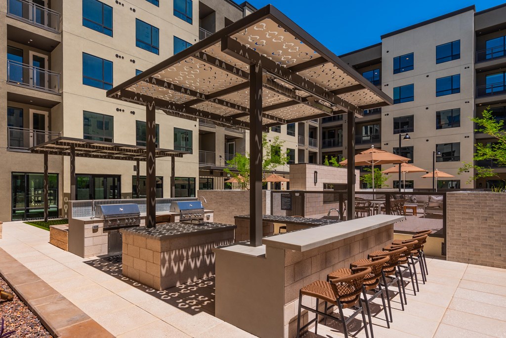 A patio with a bar and chairs under a pergola.