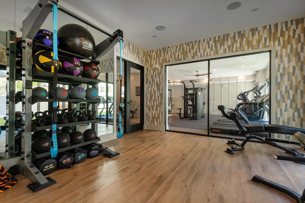 A gym with a mirrored wall and a rack of weights.