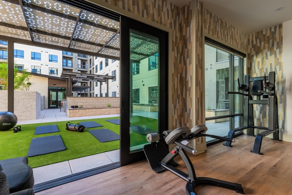 A home gym with a view of the outside through a glass door.
