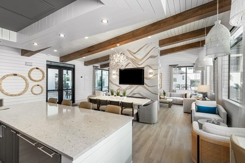 A modern kitchen with a large island and a living area with a couch and chairs.