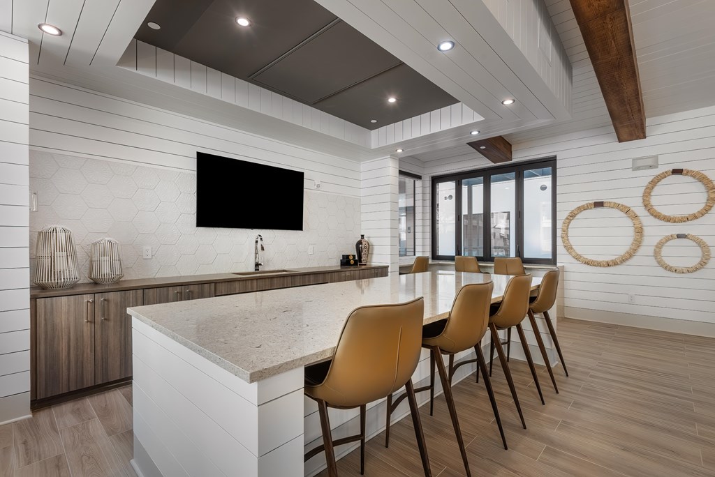 A modern kitchen with a bar and chairs.