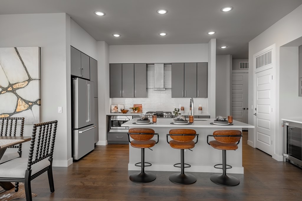A modern kitchen with a bar stool in front of the island.