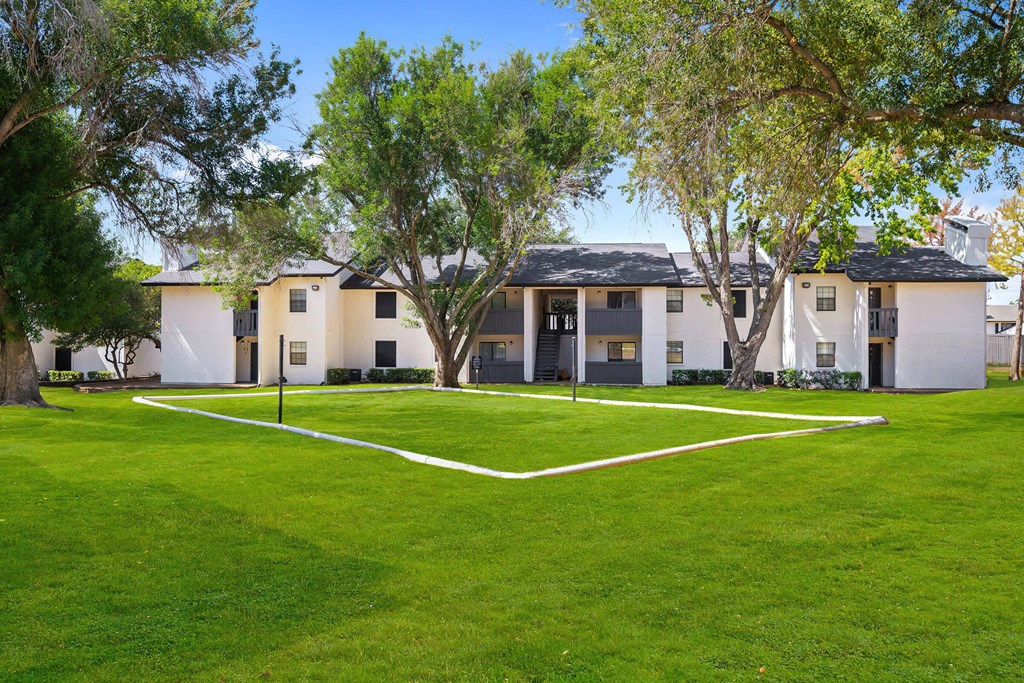 a grassy area with trees and buildings in the background