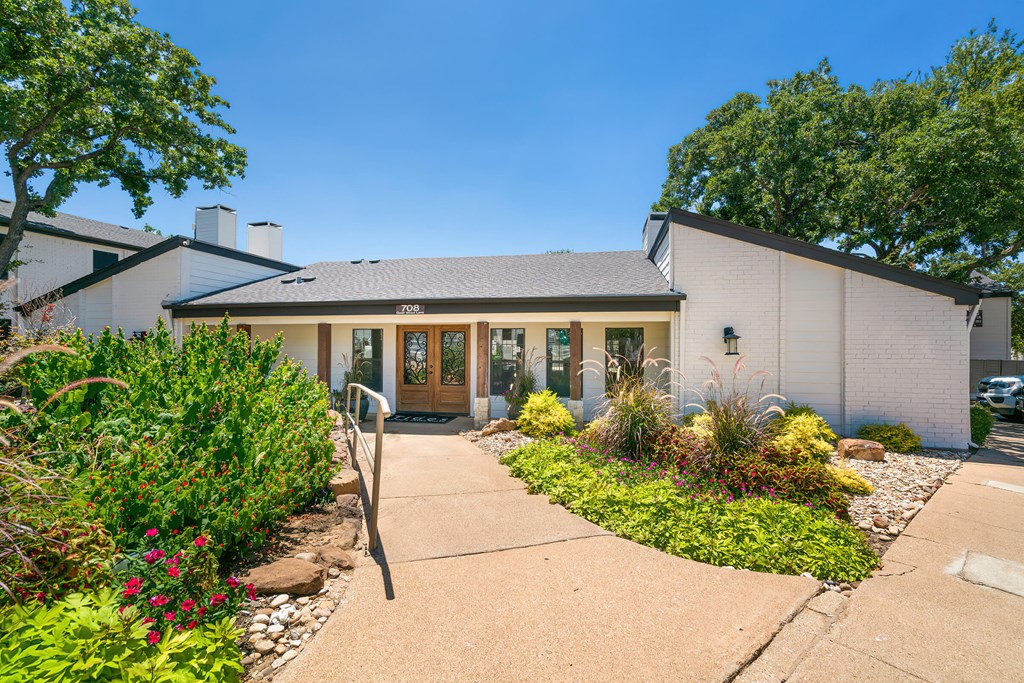 the front of a white building with a walkway in front of it