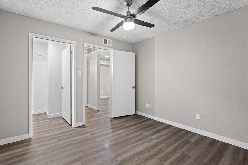 A room with a ceiling fan and three doors.