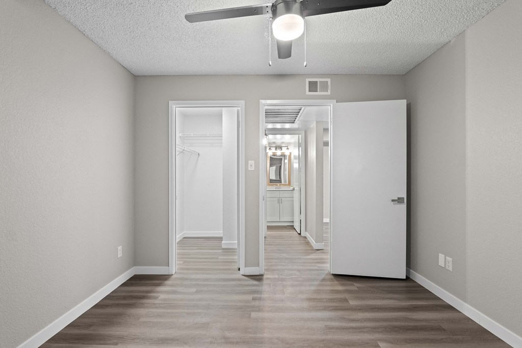 A long, empty hallway with a ceiling fan and light fixture.