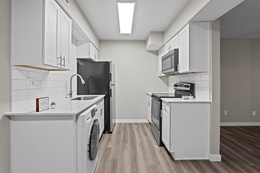 A modern kitchen with white cabinets and appliances.