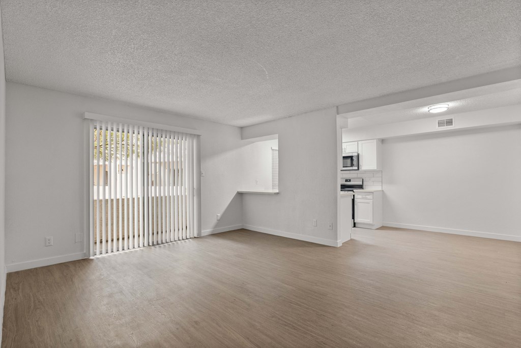 the spacious living room and kitchen of an apartment