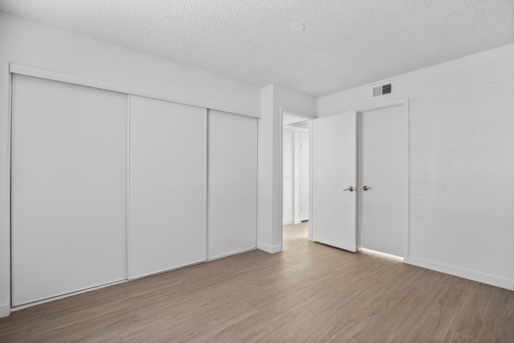an empty room with white walls and wood floors