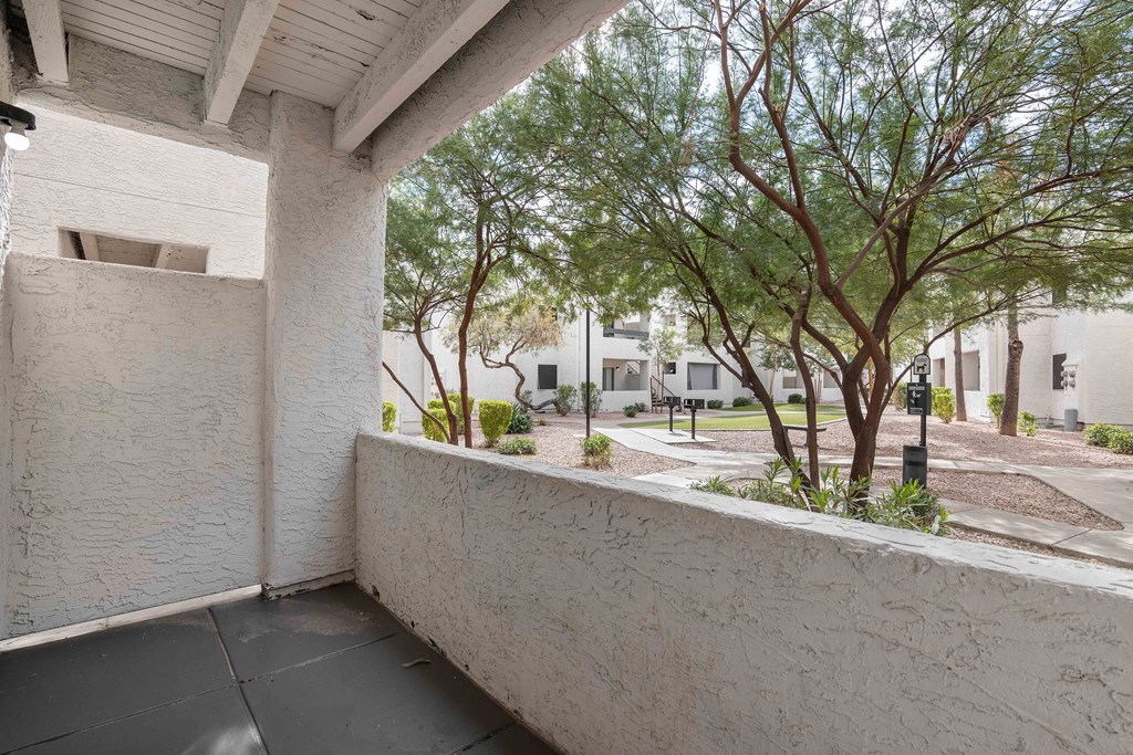 a balcony with a concrete wall and trees