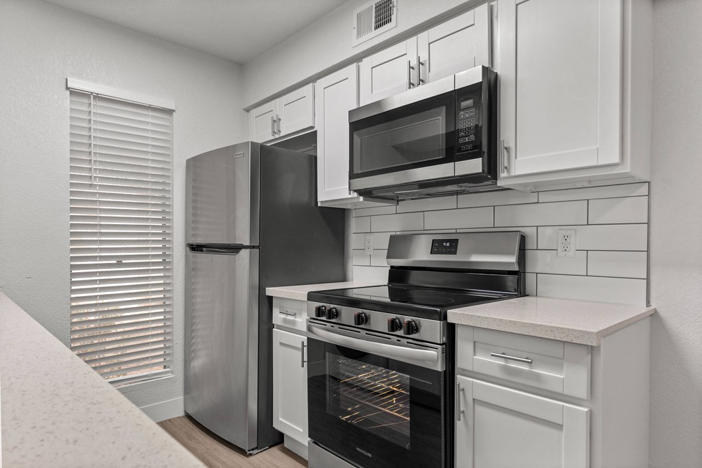 a kitchen with white cabinets and stainless steel appliances and a refrigerator