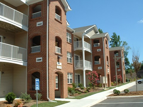 A red brick apartment building with a blue and white sign in front.
