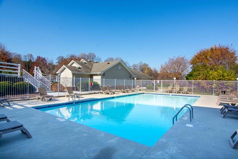 A swimming pool surrounded by a fence and chairs.