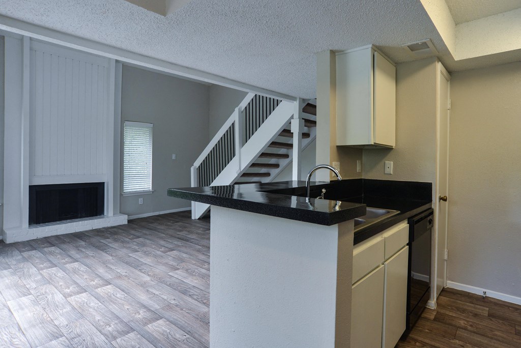an empty kitchen with a counter top and a staircase