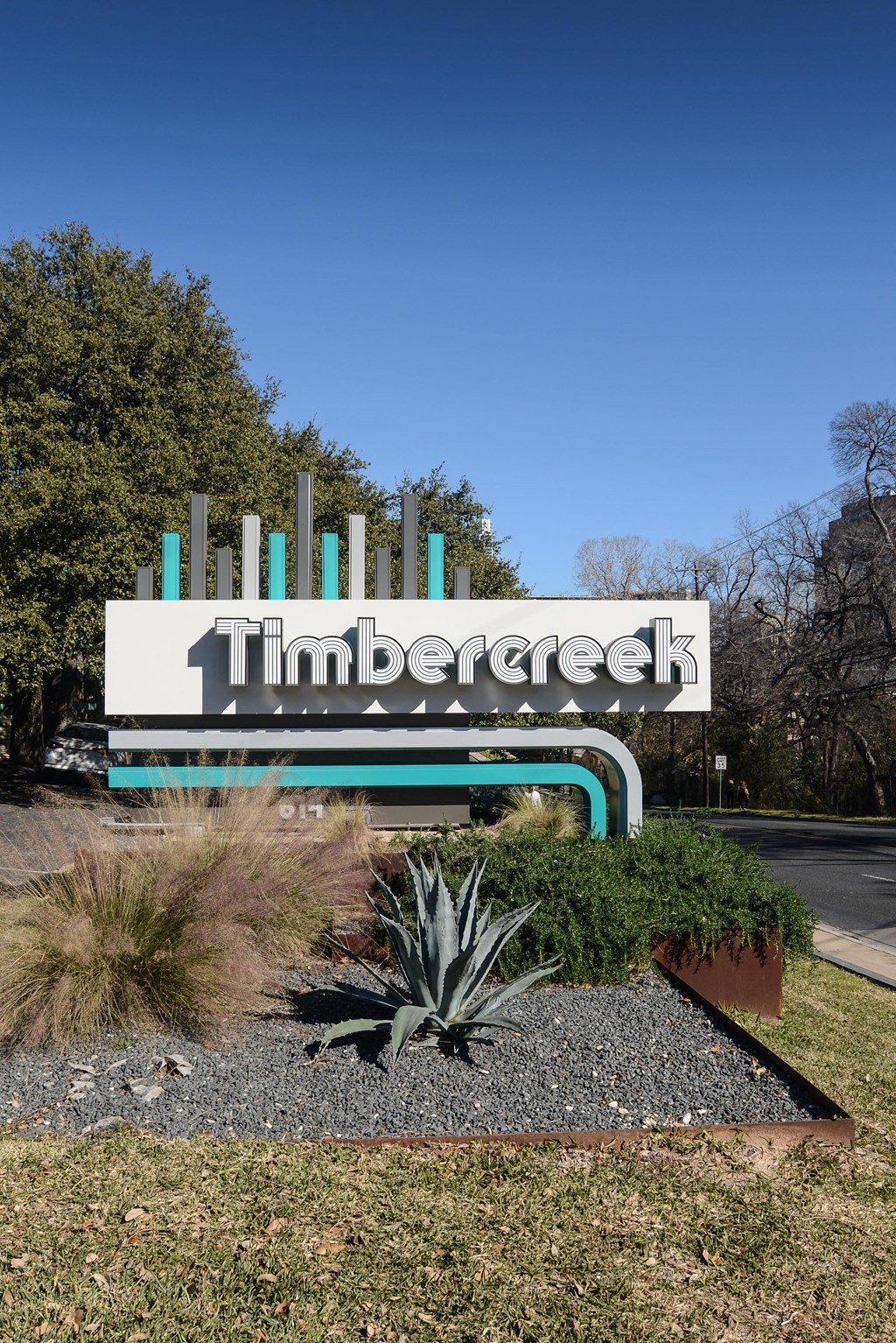 a sign for timbre creek in front of a road and trees