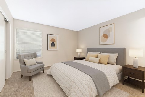 A bedroom with a bed, chair, and two lamps.