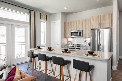 a kitchen with a large island with bar stools and a stainless steel refrigerator