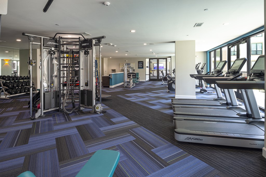 a gym with cardio machines and weights on the floor