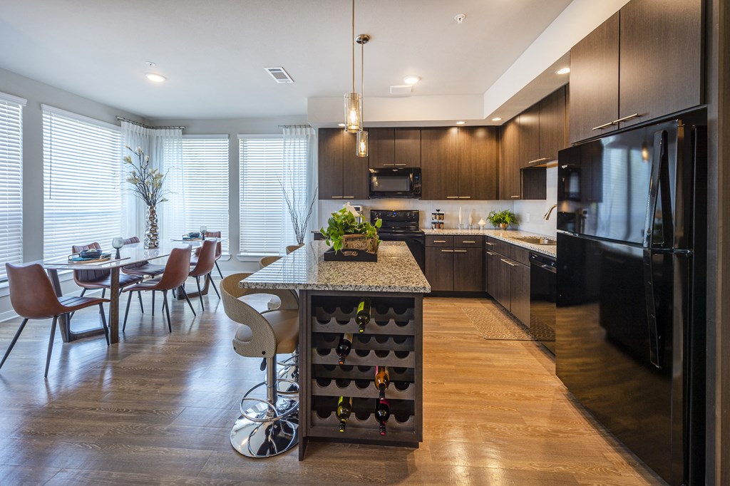 a kitchen with a bar and a dining room with a table and chairs