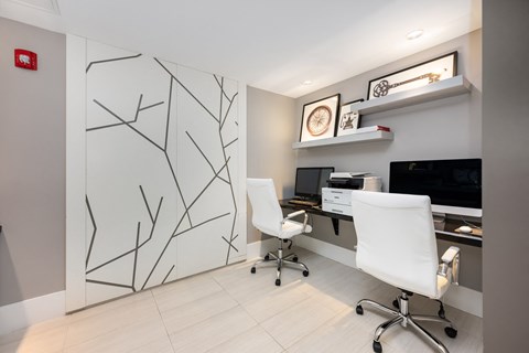a white office with two white chairs and a desk with a monitor