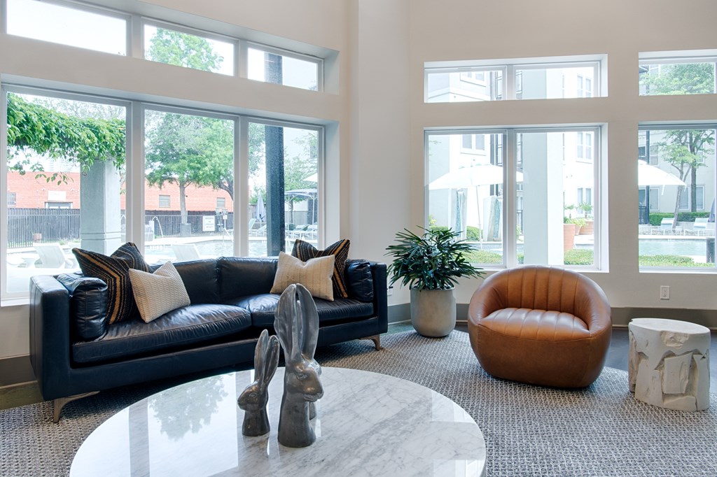 A living room with a black couch and a round orange chair.