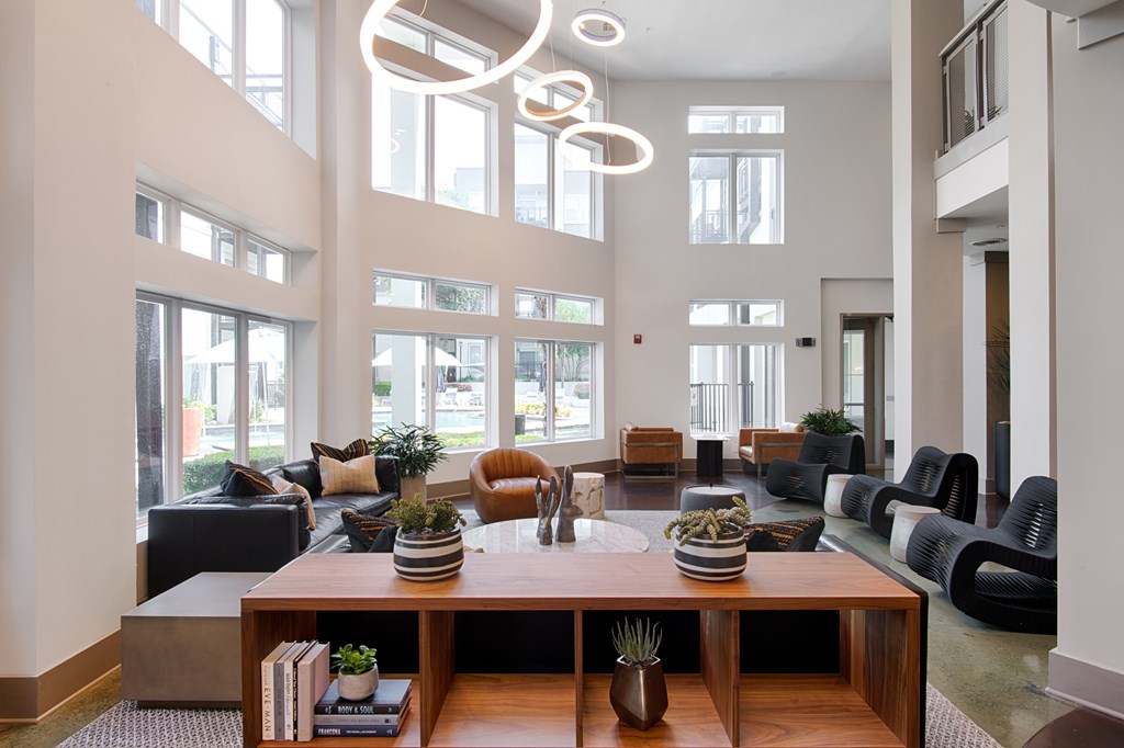 A modern living room with a large wooden coffee table and black and white furniture.